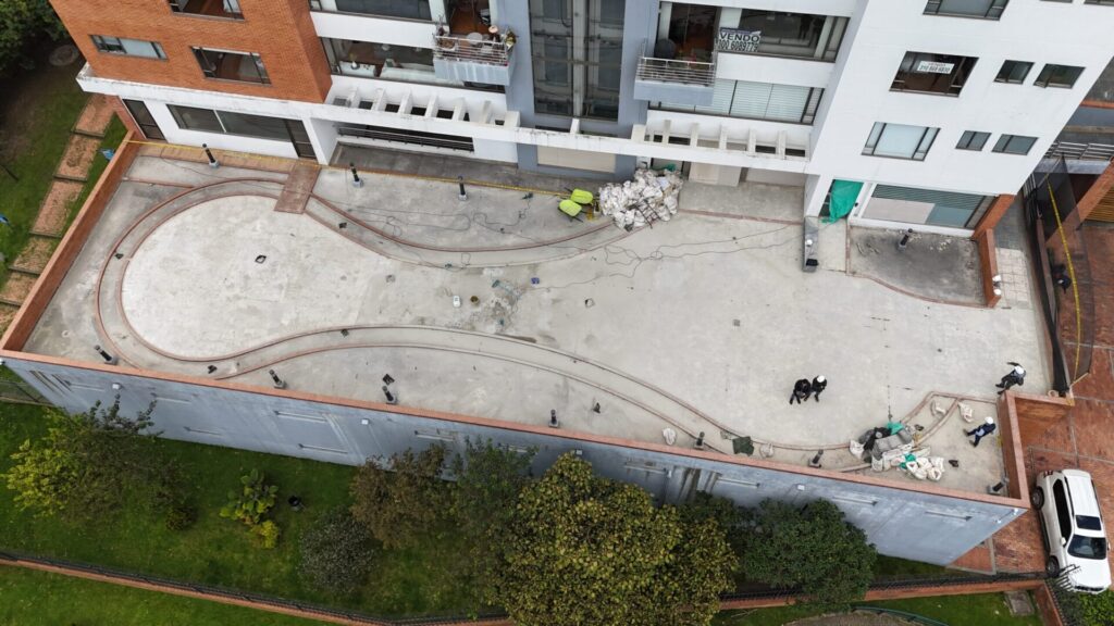Vista aerea de la plazoleta en ejecucion: base de concreto, acopio de material y frente delimitado